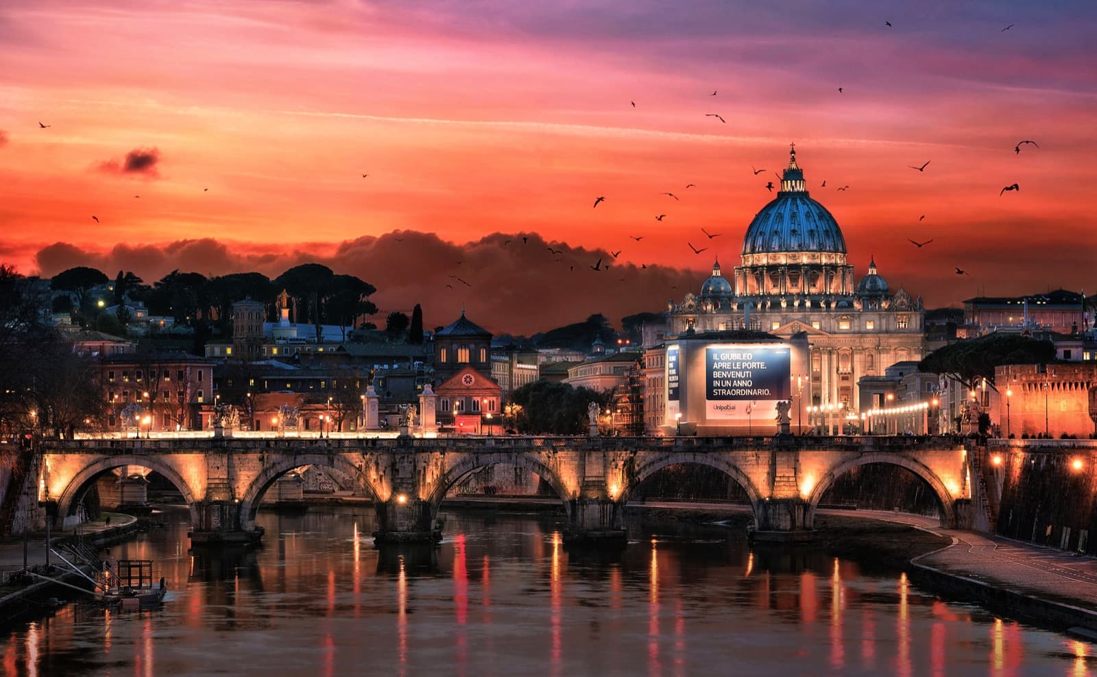 Rome illuminated at dusk: St Peter's Basilica and a lit bridge reflected in the Tiber